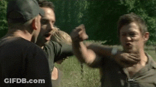 A Group Of People Are Standing In A Field And One Of Them Is Holding Another Man 'S Hand . GIF