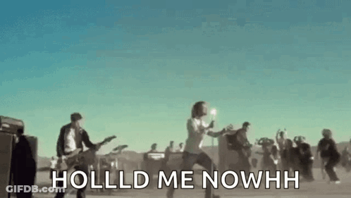 A Group Of People Are Standing In A Field Playing Guitars And Singing A Song . GIF