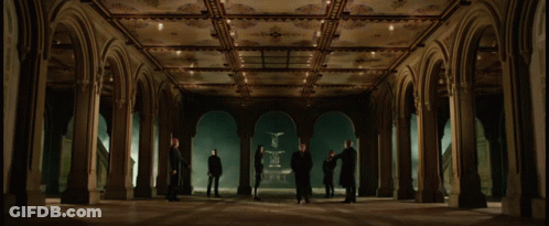 A Group Of People Are Standing In A Hallway With Arches GIF
