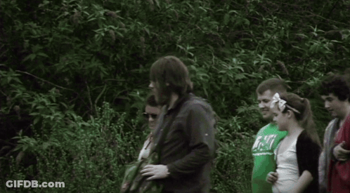 A Group Of People Are Standing In A Line And One Of Them Is Wearing A Shirt That Says ' Abercrombie ' On It GIF