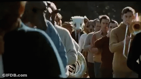 A Group Of People Are Standing In A Line Playing Musical Instruments . GIF