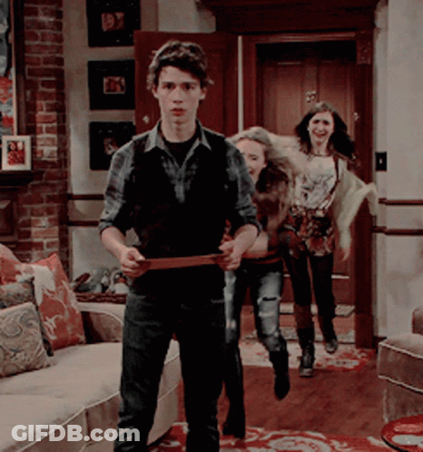 A Group Of People Are Standing In A Living Room With A Man Holding A Belt GIF