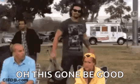 A Group Of People Are Standing In A Park And One Of Them Is Holding A Bag . GIF