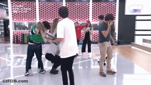 A Group Of People Are Standing In A Room And One Of Them Is Wearing A Shirt That Says ' Coco ' On The Back GIF