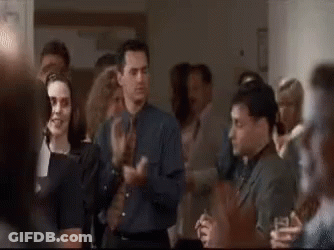 A Group Of People Are Standing In A Room Applauding Each Other . GIF