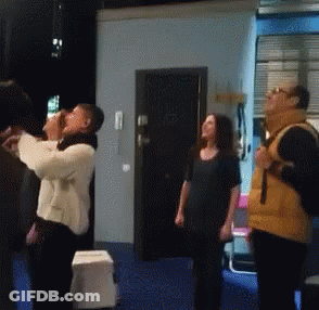 A Group Of People Are Standing In A Room Looking Up At The Sky GIF
