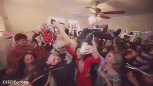 A Group Of People Are Standing In A Room With A Ceiling Fan . GIF