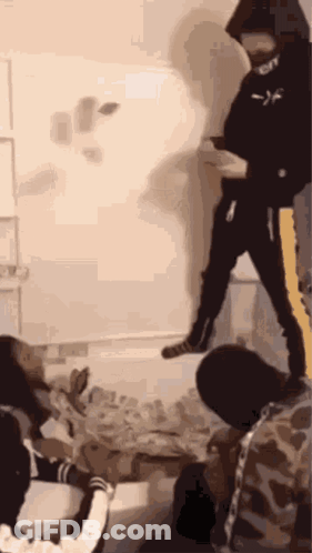 A Group Of People Are Standing In A Room With A Man In A Black Hoodie Standing In The Middle Of The Room . GIF