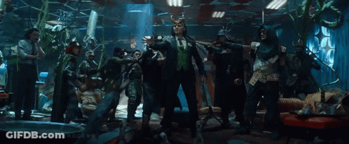 A Group Of People Are Standing In A Room With A Man In A Suit And Horns . GIF