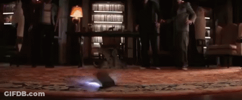 A Group Of People Are Standing In A Room With A Projector On The Floor . GIF