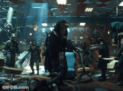 A Group Of People Are Standing In A Room With The Letter S On The Ceiling GIF