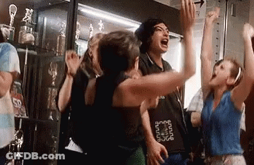 A Group Of People Are Standing In A Room With Their Arms In The Air And Screaming . GIF