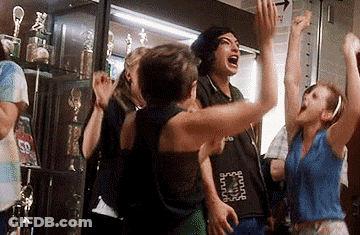 A Group Of People Are Standing In A Room With Their Arms In The Air And Screaming . GIF