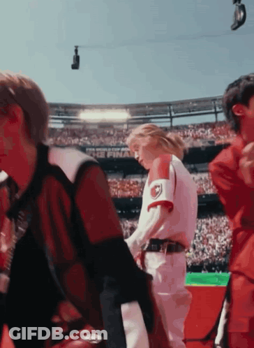 A Group Of People Are Standing In A Stadium And One Of Them Is Wearing A Red And White Jersey With The Letter R On It GIF