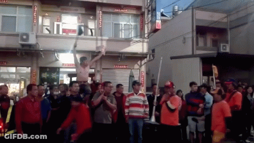 A Group Of People Are Standing In Front Of A Building With Chinese Writing On The Side GIF