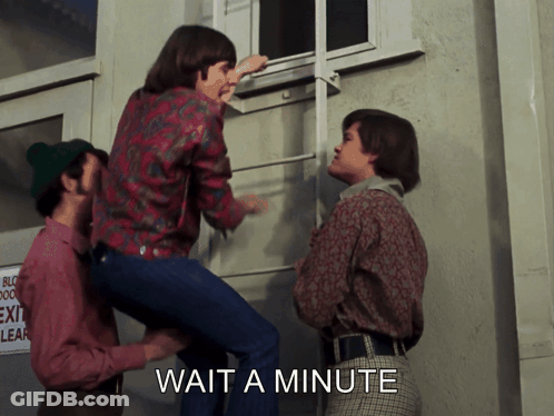 A Group Of People Are Standing In Front Of A Building With The Words Wait A Minute On The Bottom GIF