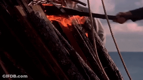A Group Of People Are Standing In Front Of A Burning Statue Of A Man GIF