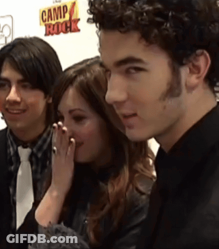 A Group Of People Are Standing In Front Of A Camp Rock Sign GIF