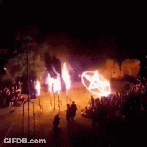 A Group Of People Are Standing In Front Of A Car That Is Burning . GIF