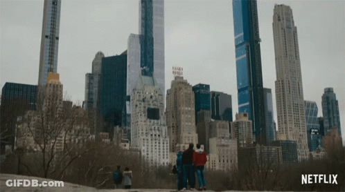 A Group Of People Are Standing In Front Of A City Skyline With A Netflix Logo In The Corner GIF