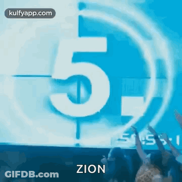 A Group Of People Are Standing In Front Of A Countdown Clock With The Number 5 On It . GIF