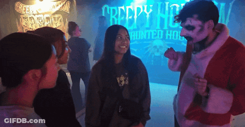 A Group Of People Are Standing In Front Of A Creepy House Sign GIF