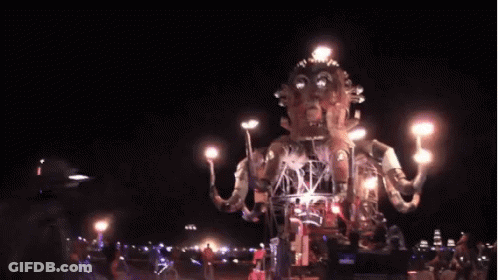 A Group Of People Are Standing In Front Of A Giant Statue Holding A Torch . GIF
