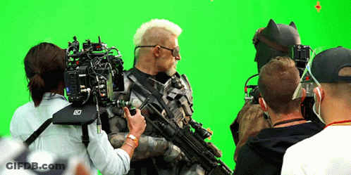A Group Of People Are Standing In Front Of A Green Screen With A Camera That Says Lx On It GIF
