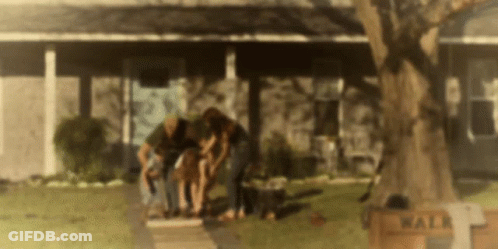A Group Of People Are Standing In Front Of A House With A Sign That Says Walk On It . GIF