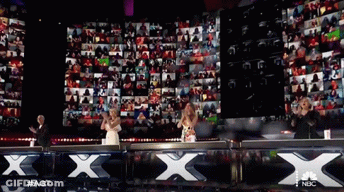 A Group Of People Are Standing In Front Of A Large Screen That Says Nbc GIF
