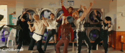 A Group Of People Are Standing In Front Of A Laundromat . GIF