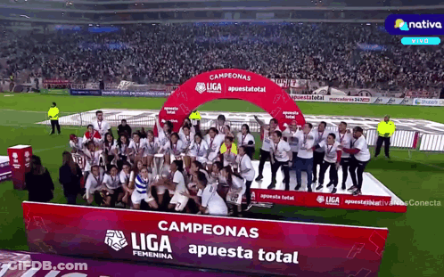 A Group Of People Are Standing In Front Of A Podium That Says Campeonas Liga Apuesta Total GIF