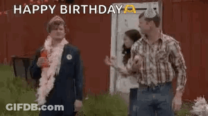 A Group Of People Are Standing In Front Of A Red Barn And One Of Them Is Wearing A Party Hat . GIF