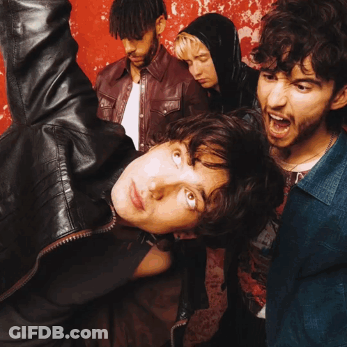 A Group Of People Are Standing In Front Of A Red Wall GIF