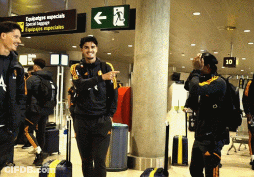 A Group Of People Are Standing In Front Of A Sign That Says Equipajes Especiales GIF