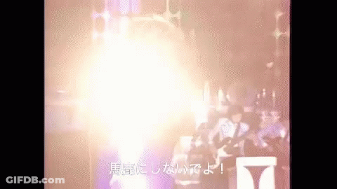 A Group Of People Are Standing In Front Of A Stage With A Huge Light Coming Out Of It . GIF