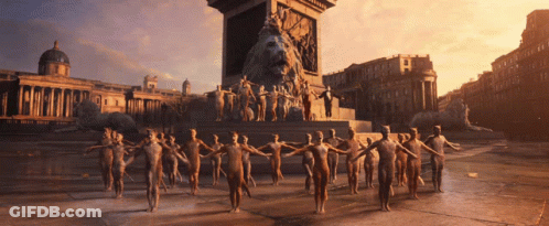 A Group Of People Are Standing In Front Of A Statue Of A Lion GIF