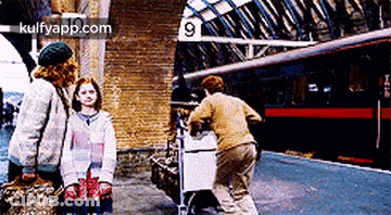 A Group Of People Are Standing In Front Of A Train Station With The Number 9 On The Sign . GIF
