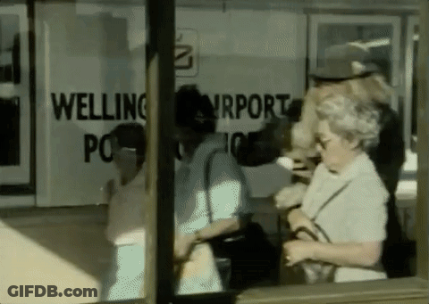 A Group Of People Are Standing In Front Of A Welling Airport Sign GIF