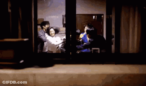 A Group Of People Are Standing In Front Of A Window And Talking To Each Other . GIF