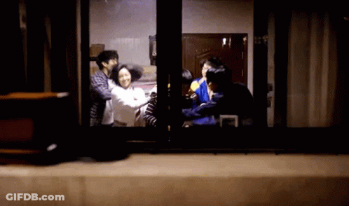 A Group Of People Are Standing In Front Of A Window In A Dark Room . GIF