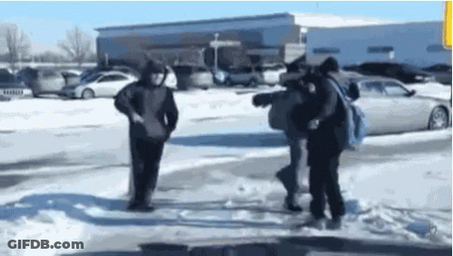 A Group Of People Are Standing In The Snow Near A Parking Lot . GIF