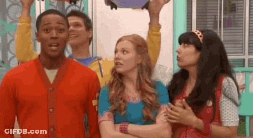 A Group Of People Are Standing Next To Each Other In A Room And One Of Them Is Holding Something In His Hand . GIF