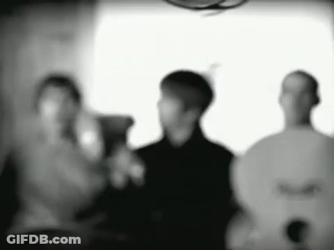 A Group Of People Are Standing Next To Each Other In A Room In A Black And White Photo . GIF