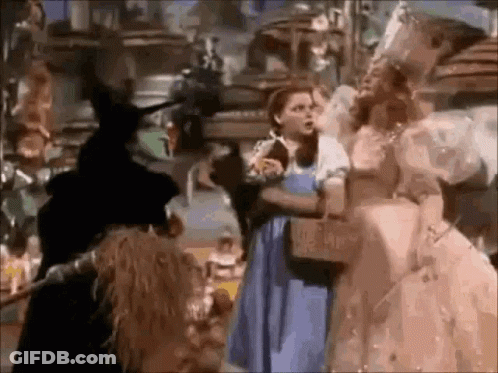 A Group Of People Are Standing Next To Each Other In A Room In A Wizard Of Oz Movie . GIF