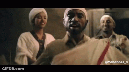 A Group Of People Are Standing Next To Each Other In A Room . One Of The Men Is Wearing A White Turban . GIF