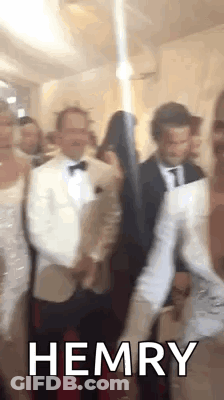 A Group Of People Are Standing Next To Each Other In A Room With The Word Hemry On The Bottom . GIF