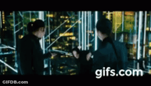 A Group Of People Are Standing Next To Each Other In Front Of A City Skyline At Night . GIF