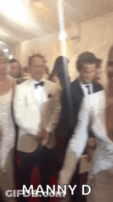 A Group Of People Are Standing Next To Each Other On A Red Carpet In A Room . GIF