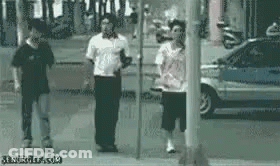 A Group Of People Are Standing Next To Each Other On A Sidewalk In Front Of A Car . GIF